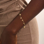 Model wearing a 14k gold dangling star bracelet with hanging charms, adding a whimsical and elegant touch.
