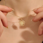 Model wearing a 14k gold flower pendant necklace with an engravable plain surface. A delicate and personalized accessory ideal for daily wear.