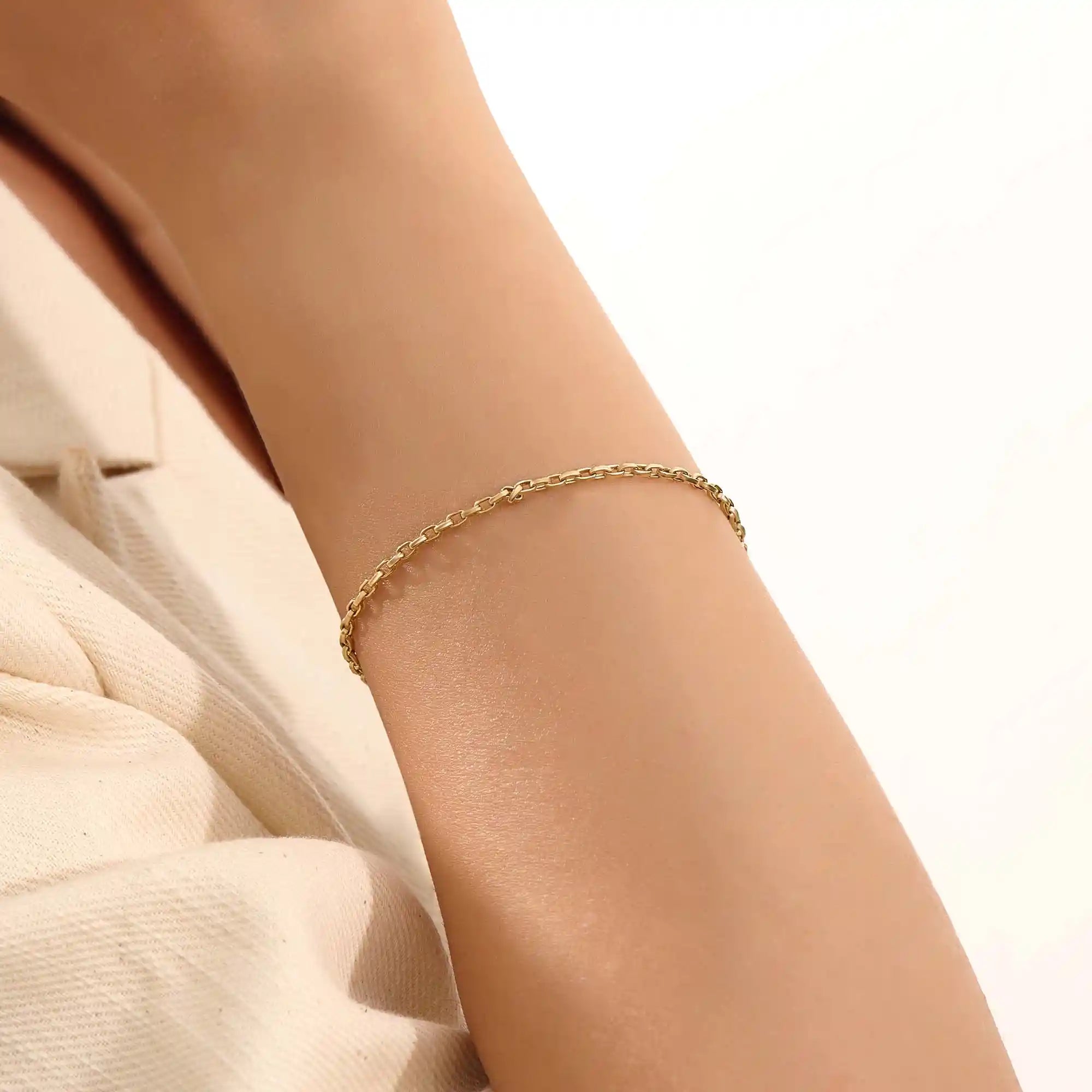 Model wearing a 14k gold rolo chain bracelet, showcasing the interlocking rectangular link design on the wrist.
