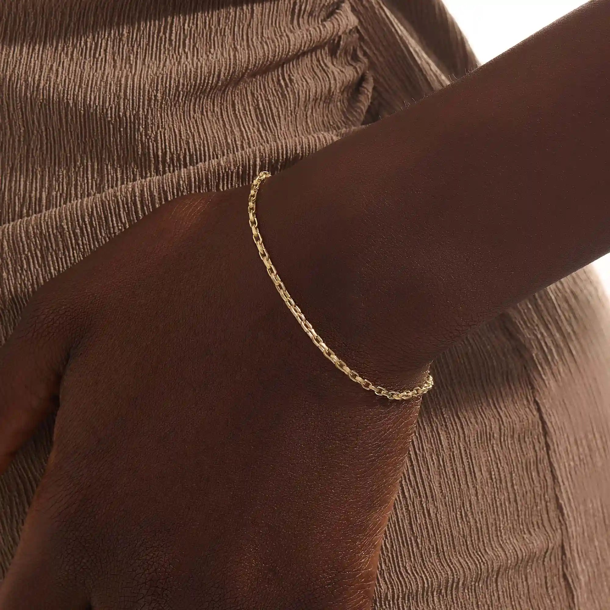 Model wearing a 14k gold rolo chain bracelet, showcasing the interlocking rectangular link design on the wrist.
