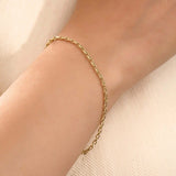 Model wearing a 14k gold rolo chain bracelet, showcasing the interlocking rectangular link design on the wrist.
