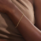 Model wearing a 14k gold rolo chain bracelet, showcasing the interlocking rectangular link design on the wrist.

