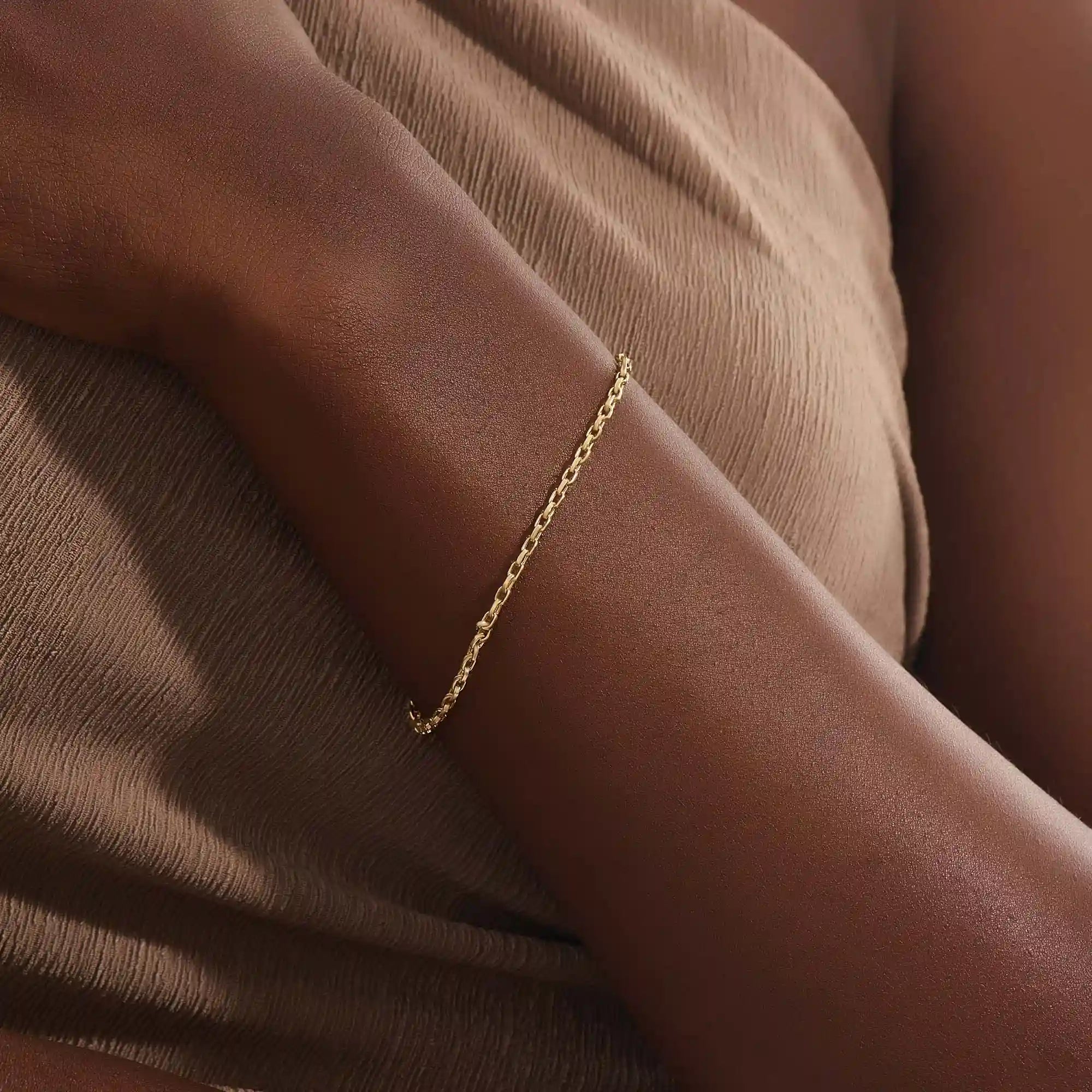 Model wearing a 14k gold rolo chain bracelet, showcasing the interlocking rectangular link design on the wrist.
