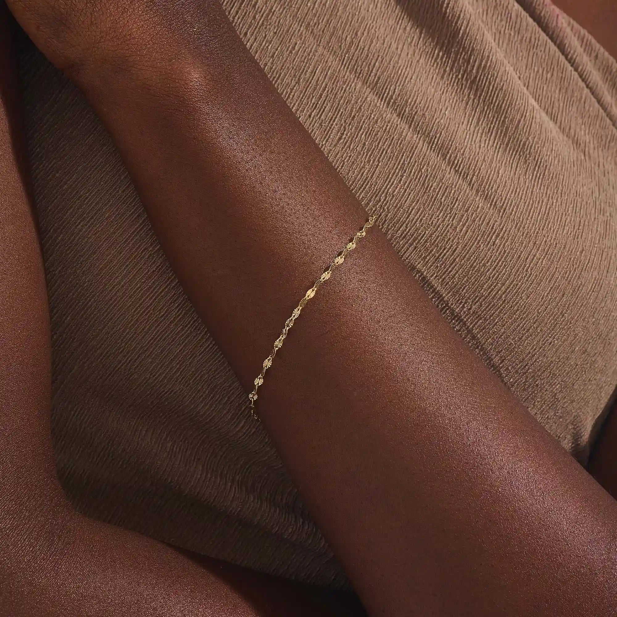 Model wearing a 14k gold textured chain bracelet, elegant with shimmering starburst accents.
