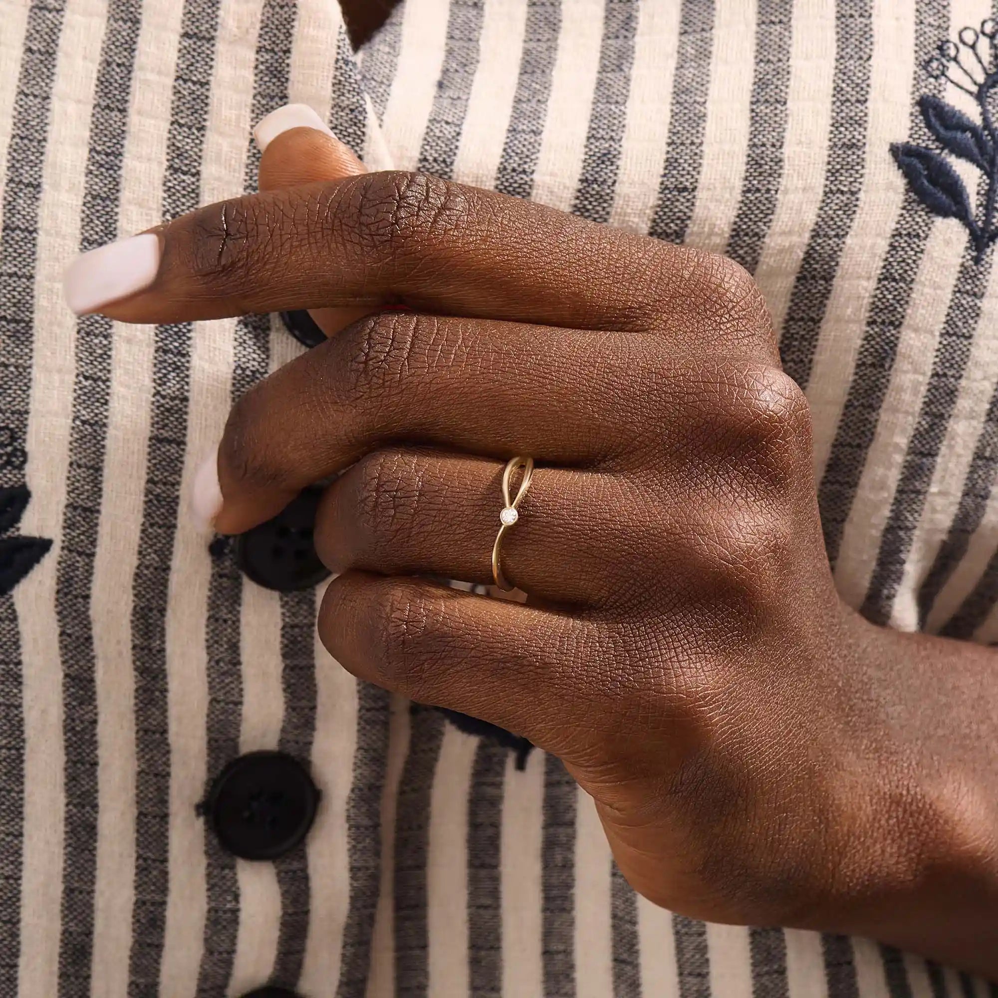 Model wearing a 14k solid gold split band promise ring with a delicate moissanite accent, showcasing a sleek and contemporary minimalist style.
