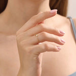 Model wearing a 14k solid gold split band promise ring with a delicate moissanite accent, showcasing a sleek and contemporary minimalist style.