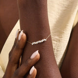 Model wearing a 14k yellow gold baguette bar bracelet with baguette-cut and round stones, adding sparkle to a refined wrist look.
