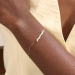 Model wearing a 14k yellow gold baguette bar bracelet with baguette-cut and round stones, adding sparkle to a refined wrist look.
