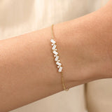 Model wearing a 14k yellow gold baguette bar bracelet with baguette-cut and round stones, adding sparkle to a refined wrist look.
