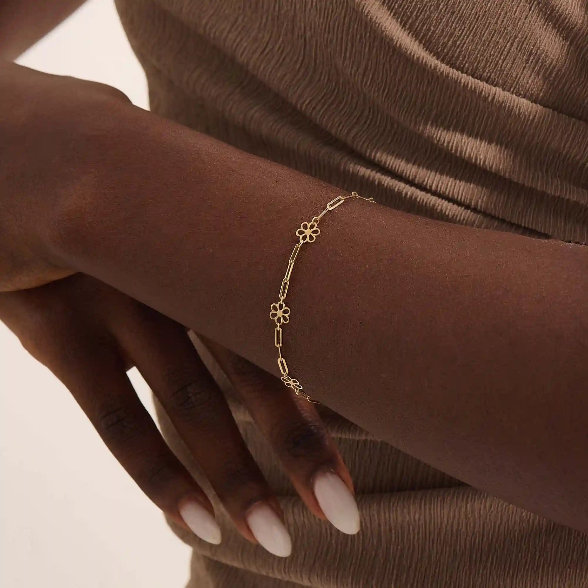 Model wearing a 14k yellow gold flower chain bracelet with delicate floral motifs for a soft, elegant style.
