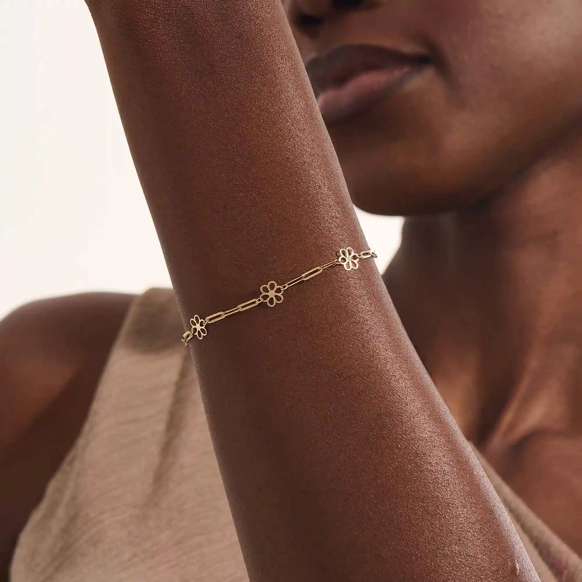 Model wearing a 14k yellow gold flower chain bracelet with delicate floral motifs for a soft, elegant style.
