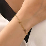 Model wearing a 14k yellow gold flower chain bracelet with delicate floral motifs for a soft, elegant style.
