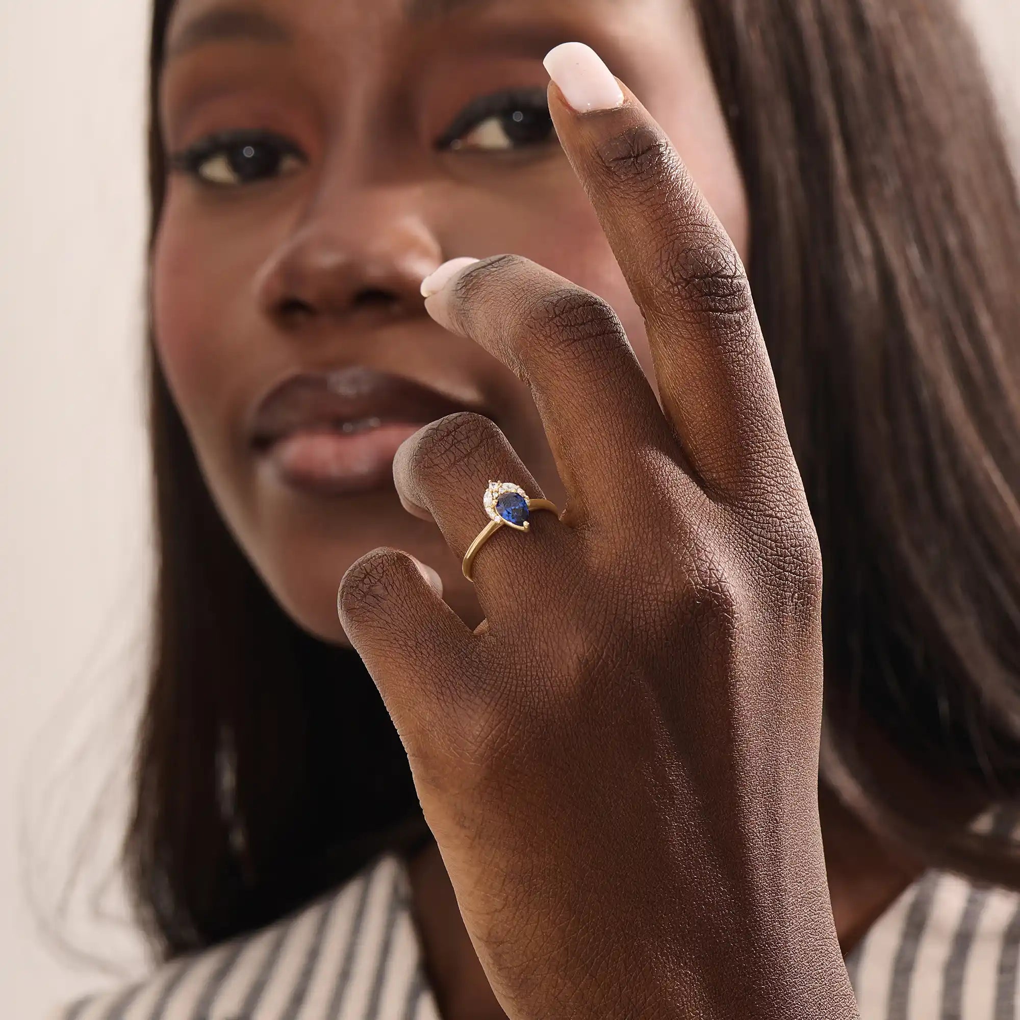 Model wearing a pear-shaped sapphire ring with moissanite accents in solid gold. A refined gemstone ring for special occasions or daily elegance.