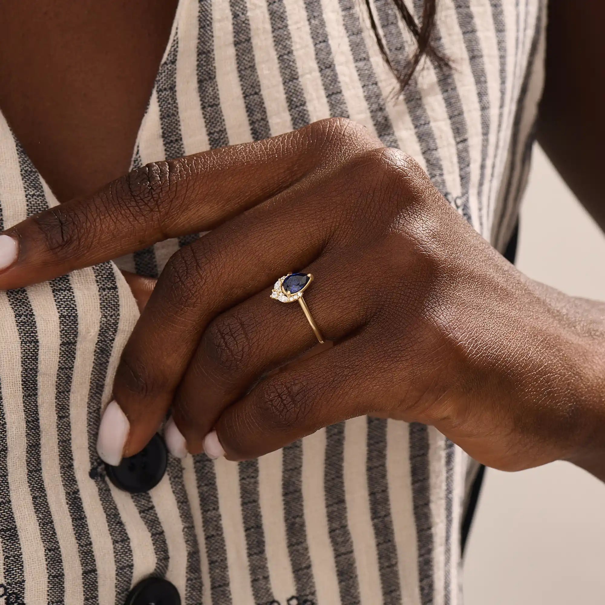 Model wearing a pear-shaped sapphire ring with moissanite accents in solid gold. A refined gemstone ring for special occasions or daily elegance.