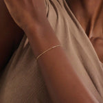Model wearing a slim 14k gold link chain bracelet with elongated links, styled for everyday wear.
