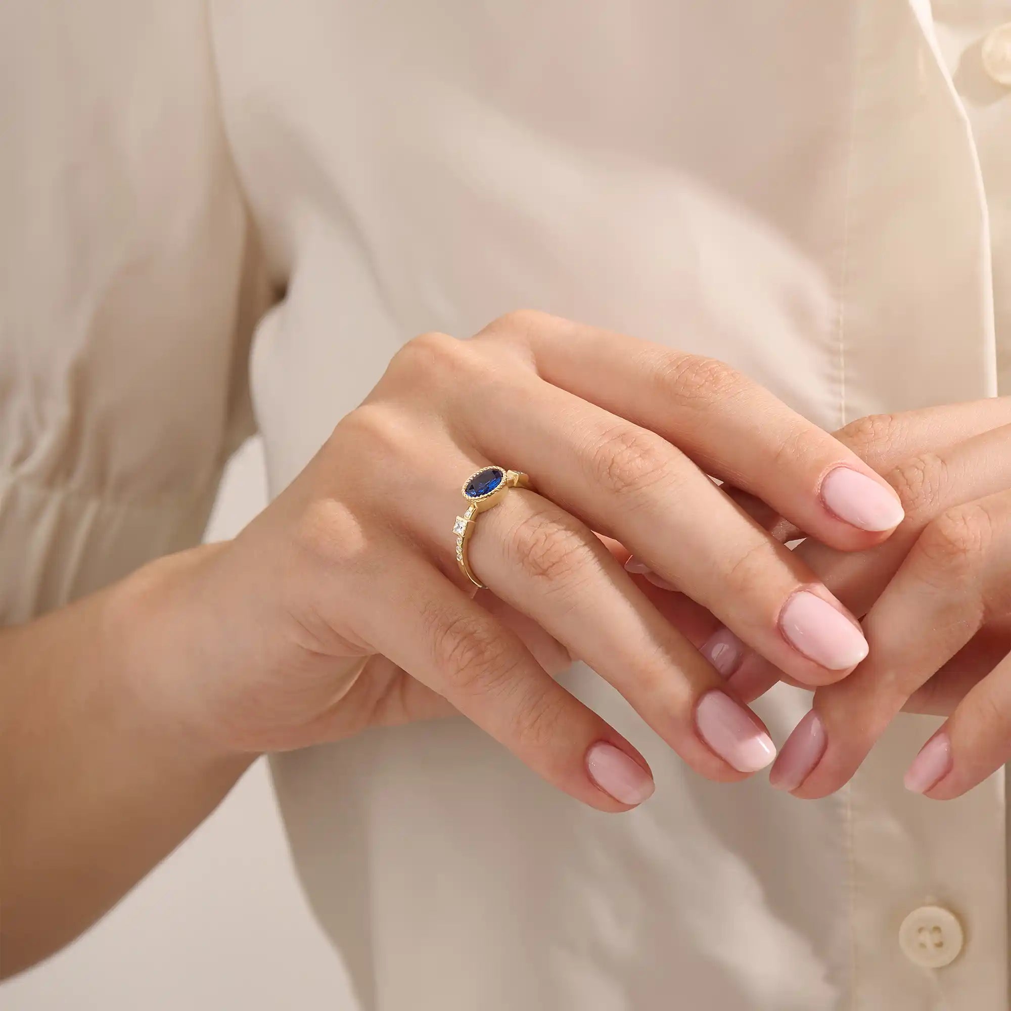 Model wearing a vintage bezel set oval sapphire ring with moissanite accents. Elegant 14k gold solitaire gemstone ring for everyday or engagement.