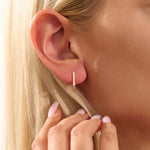 Model wearing minimalist U-shape hoop earrings in 14k gold, highlighting the sleek geometric design.
