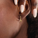 Model wearing minimalist U-shape hoop earrings in 14k gold, highlighting the sleek geometric design.
