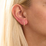 Model wearing minimalist U-shape hoop earrings in 14k gold, highlighting the sleek geometric design.
