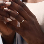 Model wearing minimalist cluster moissanite stacking wedding ring in 14k solid gold, showcasing a delicate round stone arrangement and sleek band design.