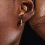 Model wearing twist rope hoop earrings in 14k gold with moissanite accents, showcasing their textured elegance.
