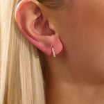 Model wearing twist rope hoop earrings in 14k gold with moissanite accents, showcasing their textured elegance.
