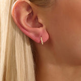 Model wearing twist rope hoop earrings in 14k gold with moissanite accents, showcasing their textured elegance.
