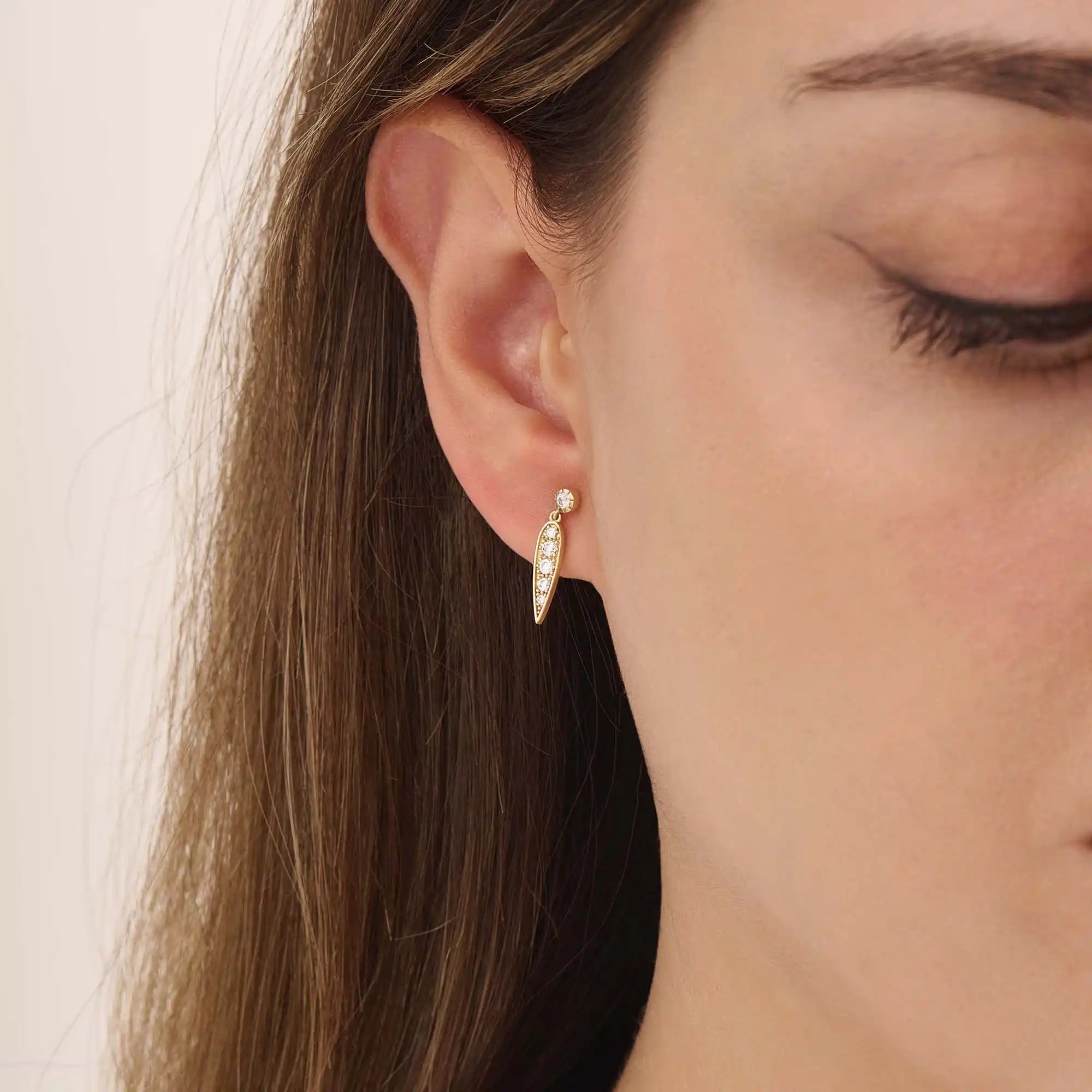 Model wears 14k gold dangling leaf stud earrings, adding a subtle botanical charm to any outfit.