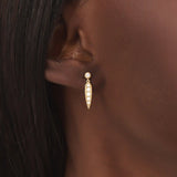 Model wears 14k gold dangling leaf stud earrings, adding a subtle botanical charm to any outfit.