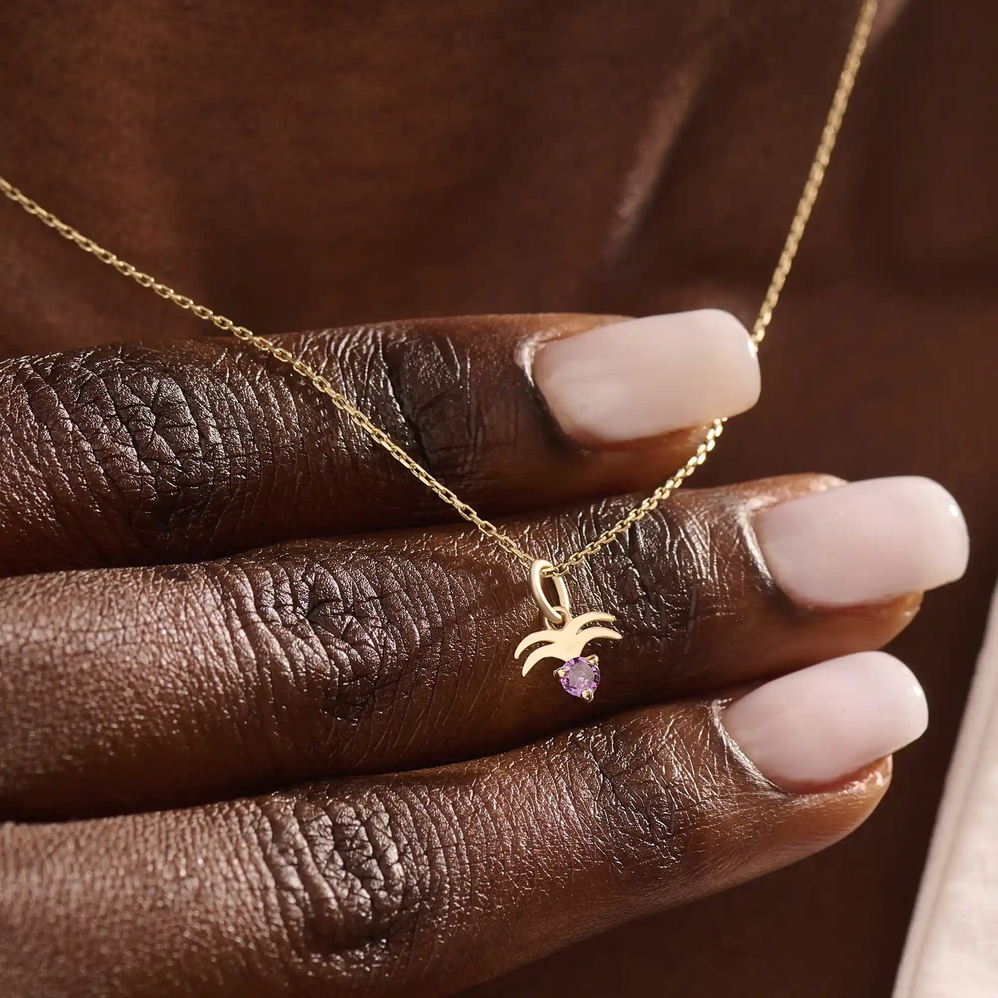 Model wears a 14k gold Aquarius zodiac pendant necklace featuring amethyst. Perfect for Aquarius zodiac birthdays and gifts.