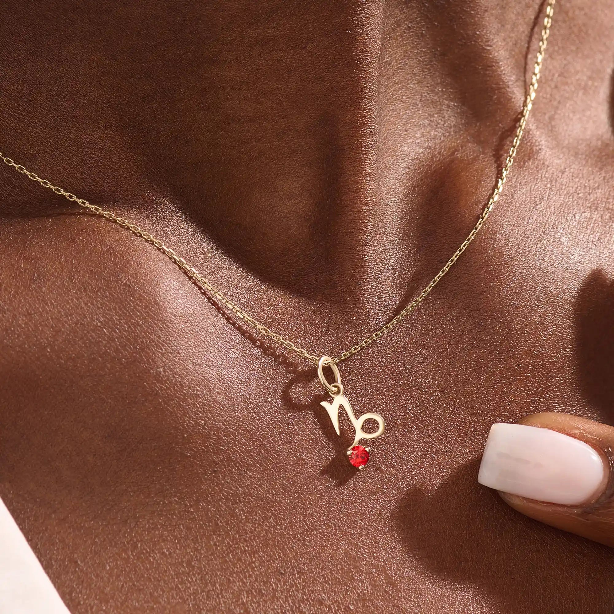Model wears a 14k gold Capricorn zodiac necklace with a garnet birthstone accent. Elegant and symbolic jewelry for daily wear.