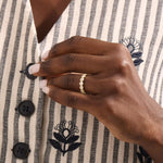 Model wears a 14k gold bold dots band ring with pave moissanites. Eye-catching statement piece for everyday style.