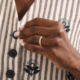 Model wears a 14k gold bold dots band ring with pave moissanites. Eye-catching statement piece for everyday style.
