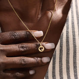 Model wears a 14k gold circle pendant necklace with a heart cutout and single moissanite accent. A minimalist and elegant everyday piece.