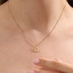 Model wears a 14k gold circle pendant necklace with a heart cutout and single moissanite accent. A minimalist and elegant everyday piece.