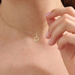 Model wears a 14k gold circle pendant necklace with a heart cutout and single moissanite accent. A minimalist and elegant everyday piece.