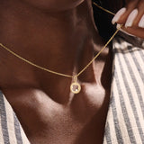 Model wears a 14k gold circle pendant necklace with clover cutout and single moissanite accent. A minimalist and meaningful everyday accessory.