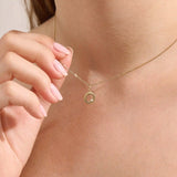 Model wears a 14k gold circle pendant necklace with clover cutout and single moissanite accent. A minimalist and meaningful everyday accessory.