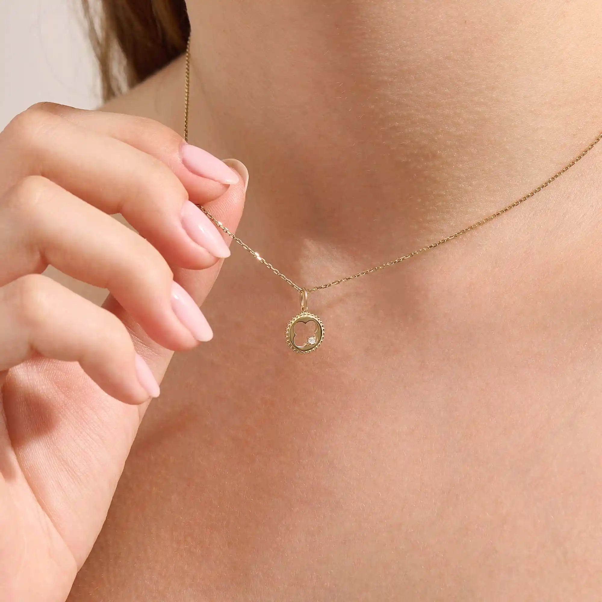 Model wears a 14k gold circle pendant necklace with clover cutout and single moissanite accent. A minimalist and meaningful everyday accessory.
