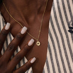 Model wears a 14k gold circle pendant necklace with star cutout and single moissanite accent. A minimalist and elegant everyday jewelry piece.