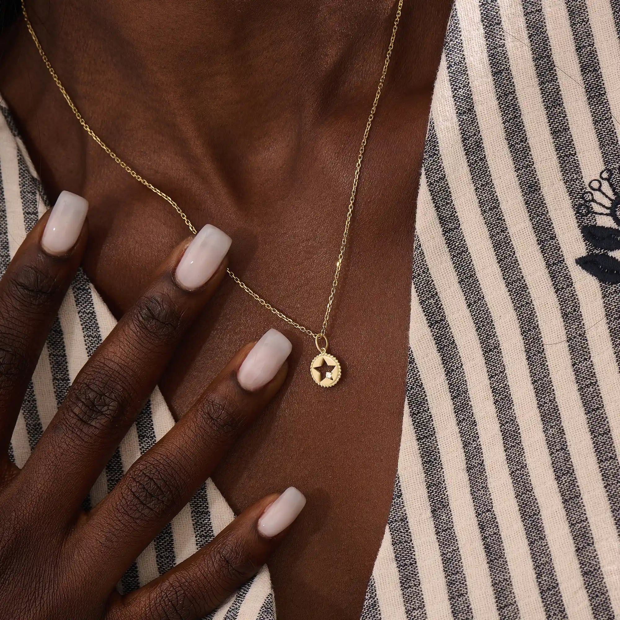 Model wears a 14k gold circle pendant necklace with star cutout and single moissanite accent. A minimalist and elegant everyday jewelry piece.