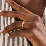 Model wears a 14k gold crossover band promise ring featuring delicate moissanite accents. A stylish and modern symbol of commitment.