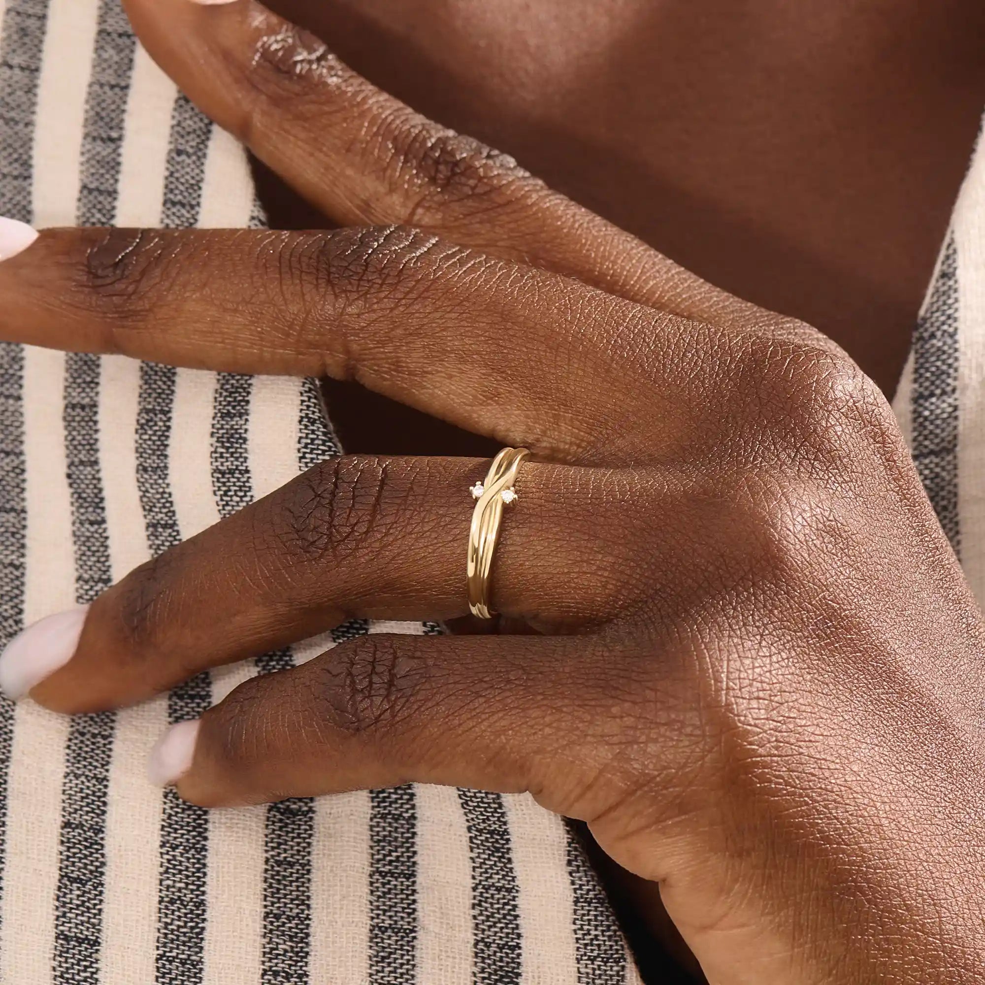 Model wears a 14k gold crossover band promise ring featuring delicate moissanite accents. A stylish and modern symbol of commitment.