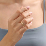 Model wears a 14k gold crossover band promise ring featuring delicate moissanite accents. A stylish and modern symbol of commitment.