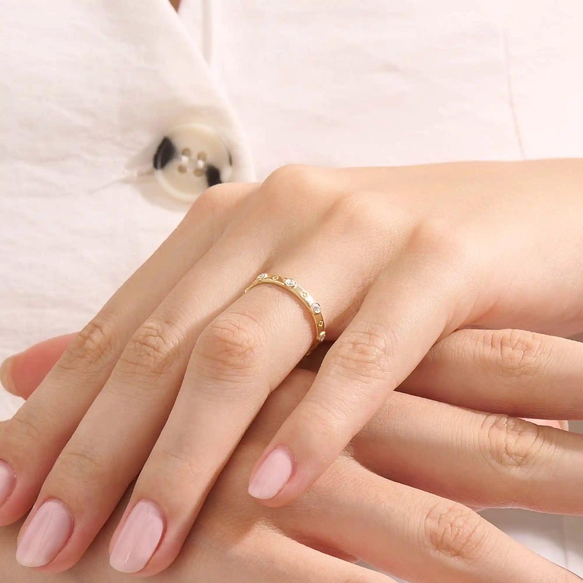 Model wears a 14k gold minimalist band ring with bezel moissanites around the band. Perfect everyday statement ring.