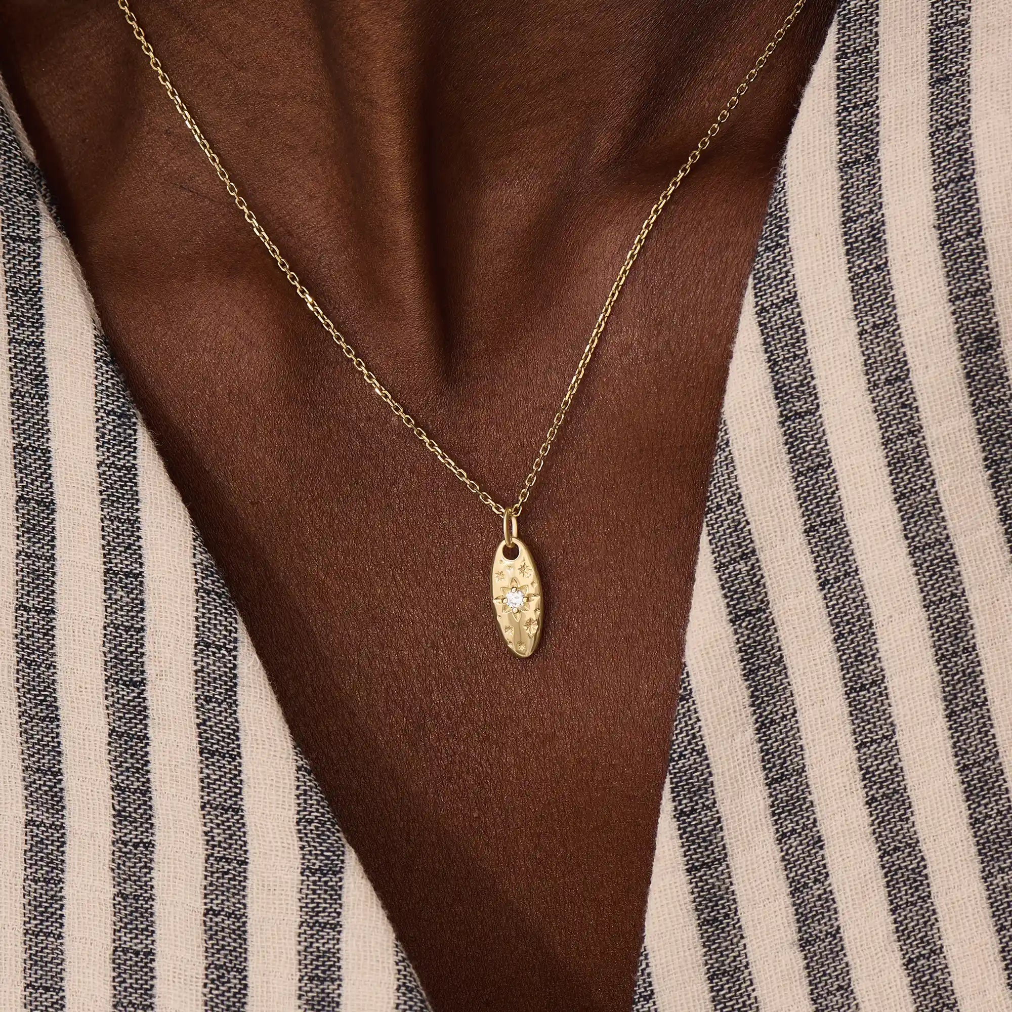 Model wears a 14k gold oval celestial pendant necklace with moissanite Northstar detail. A refined and meaningful accessory for everyday wear.