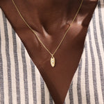 Model wears a 14k gold oval celestial pendant necklace with moissanite Northstar detail. A refined and meaningful accessory for everyday wear.