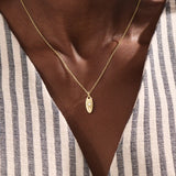 Model wears a 14k gold oval celestial pendant necklace with moissanite Northstar detail. A refined and meaningful accessory for everyday wear.