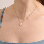 Model wears a 14k gold oval celestial pendant necklace with moissanite Northstar detail. A refined and meaningful accessory for everyday wear.
