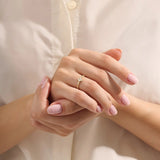 Model wears a 14k gold pinky signet ring featuring a clover-shaped moissanite and textured beaded band. Elegant and meaningful everyday jewelry.